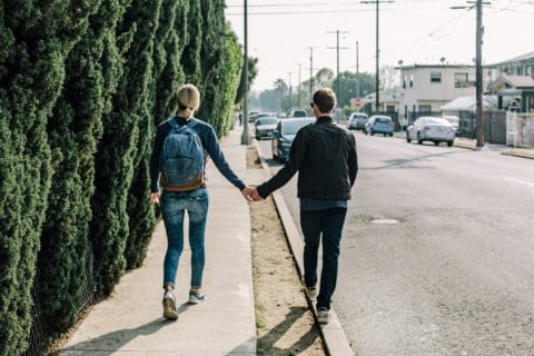 two people walking in city holding hands