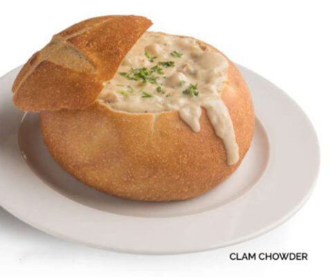 Clam chowder in a sourdough bread bowl served on a white plate