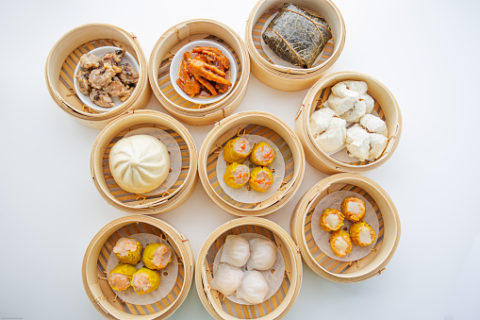 Steam baskets full of different types of dim sum on a white table