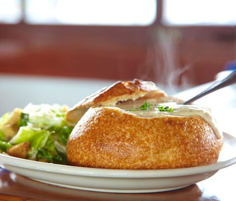 Clam chowder in a sourdough bread bowl served on a white plate