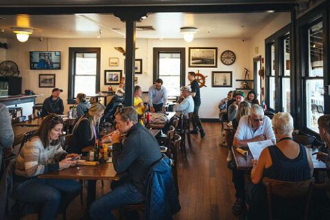 Interior shot of Eagle Cafe at PIER 39 in San Francisco filled with customers with historical memorabilia on the walls